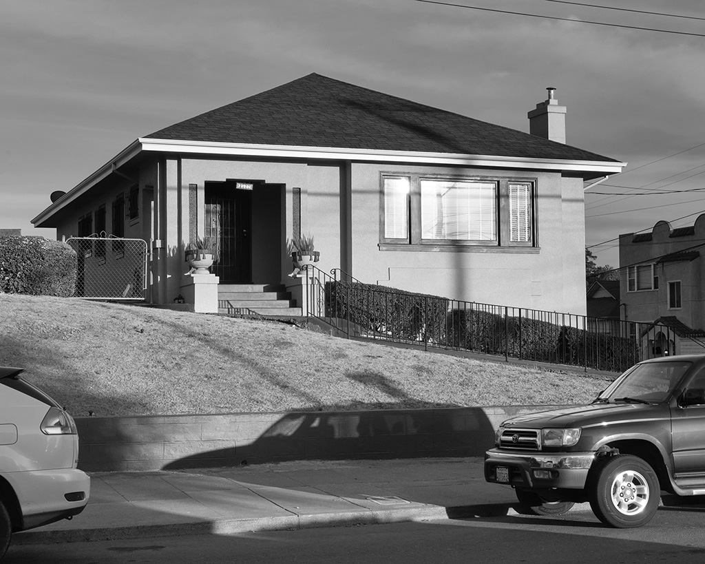 A black and white photograph of a house in bright sunlight in Oakland, California