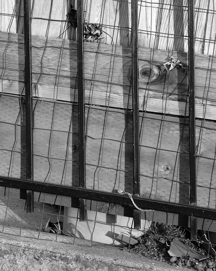 A close up abstract black and white photograph depicting layers of fences in Oakland, California